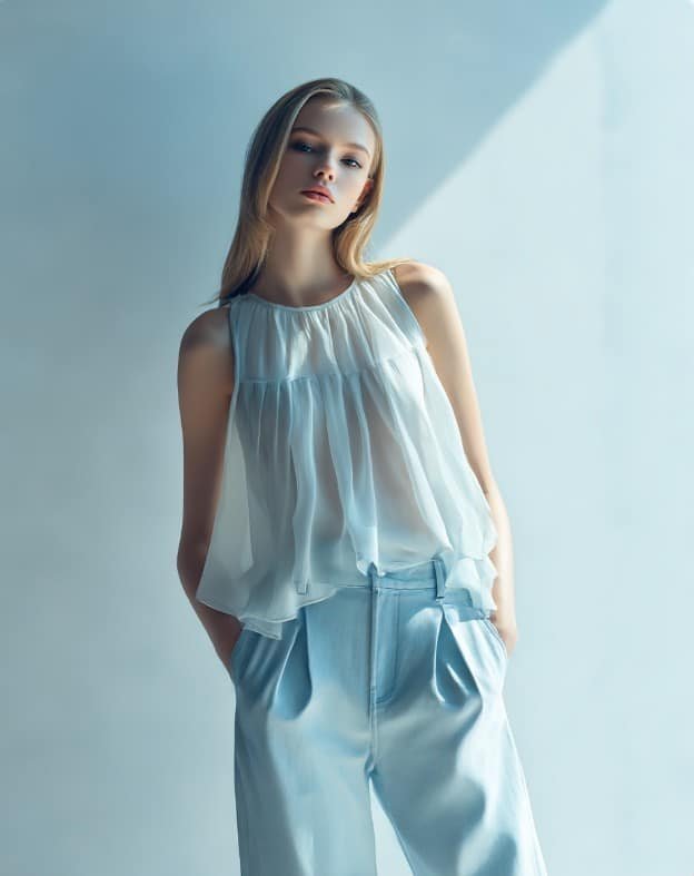 Athletic body type model styling a flowy babydoll top with structured trousers
