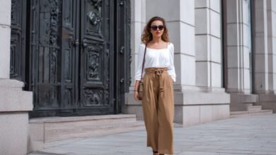 White babydoll top styled with high-waisted wide trousers and sunglasses