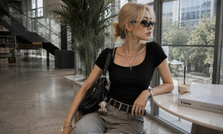Acubi accessories outfit with black shoulder bag, silver jewelry, sunglasses, belt hardware, fitted black top, grey denim, and modern cafe styling