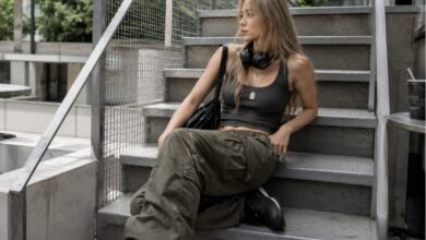 Acubi cargo pants outfit with black fitted tank, olive cargo pants, chunky black sneakers, black shoulder bag, headphones, silver jewelry, and modern city styling