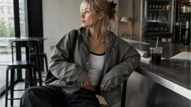 Acubi jacket outfit with oversized grey utility jacket, fitted white tank, dark loose pants, black shoulder bag, silver jewelry, and modern cafe styling