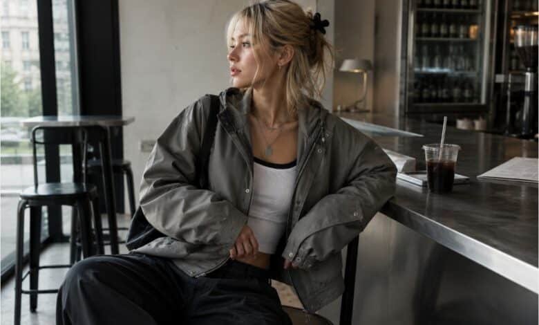 Acubi jacket outfit with oversized grey utility jacket, fitted white tank, dark loose pants, black shoulder bag, silver jewelry, and modern cafe styling