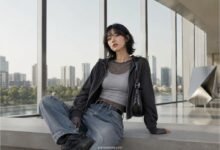 Acubi layering outfit with mesh top, grey fitted tank, black zip hoodie, baggy jeans, black shoulder bag, chunky sneakers, and muted city styling