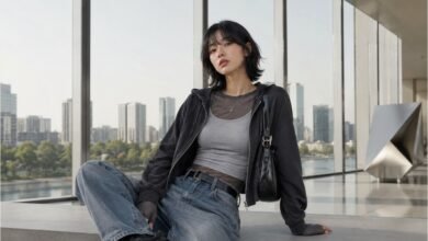 Acubi layering outfit with mesh top, grey fitted tank, black zip hoodie, baggy jeans, black shoulder bag, chunky sneakers, and muted city styling