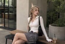 Acubi skirt outfit with white fitted zip top, grey cargo skirt, black shoulder bag, silver jewelry, black belt, and muted café styling