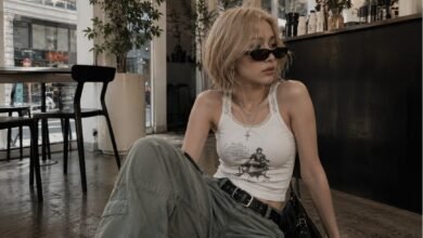 Acubi tops outfit with a fitted white tank, cargo pants, black shoulder bag, sunglasses, silver jewelry, and modern city cafe styling