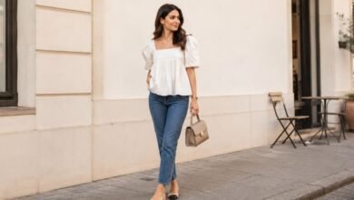 Woman wearing a white babydoll top with straight-leg jeans on a stylish city street