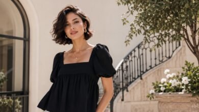 Woman wearing a black babydoll top with cream trousers in a clean elegant courtyard outfit
