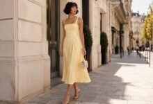 Stylish woman in a butter yellow midi dress with gold sandals on an elegant Paris street in soft sunlight