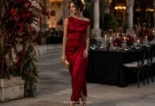 Woman in an elegant red satin wedding guest dress at an evening garden wedding reception