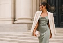 Woman in a sage satin dress and beige blazer styled for a city hall wedding guest outfit