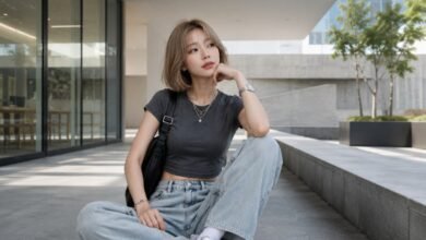 Acubi outfit with basic clothes, fitted charcoal tee, loose light denim, white sneakers, black bag, silver jewelry, and modern city styling