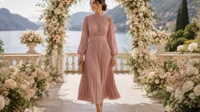 Modest wedding guest dress with long sleeves under a romantic floral wedding arch by the lake