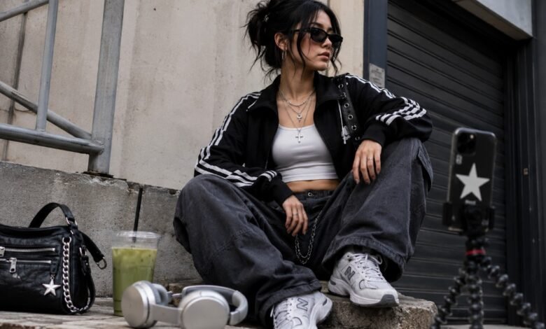 Acubi-inspired TikTok fashion street style with sporty jacket, baggy cargo jeans, chunky sneakers, silver accessories, phone tripod, and headphones