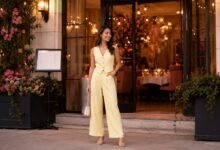 Stylish guest arriving at a friend’s birthday dinner in a pale yellow tailored jumpsuit with heels and a small handbag.
