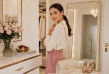 Three-point outfit check with a polished cream blouse, rose trousers, structured handbag, mirror, flowers, fruit, and elegant styling details