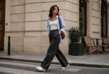 Woman styling white canvas sneakers with charcoal wide-leg trousers, a white tank and an oversized blue shirt for a polished city outfit