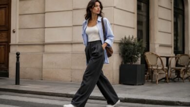 Woman styling white canvas sneakers with charcoal wide-leg trousers, a white tank and an oversized blue shirt for a polished city outfit