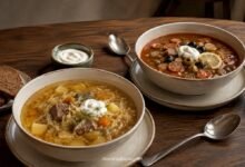 Traditional sour shchi beside meat solyanka with pickles, olives, lemon and sour cream